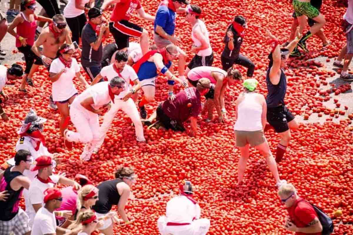 people throwing tomatoes at themselves at a food festival