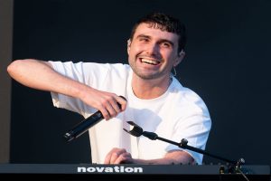 Fred again.. holding a microphone during a live performance, representing the energy of Emerging Indie Artists