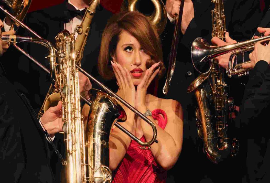 Singer Raye surrounded by instrumentalist