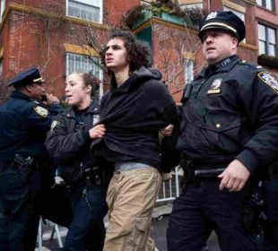 A teenager led by the police in the Two teenagers face charges over an alleged bomb attempt during a protest in New York, raising fresh concerns about security and a possible New York terror threat.