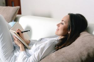 A woman feeling relaxed while journaling, illustrating how journaling can Improve your life