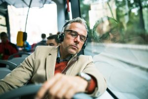 A man putting on a headphone while travelling, a representation of an essential Travel gadgets