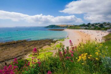 Scenic view of charming UK coastal towns with sandy beaches, colorful houses, and summer seaside atmosphere along the coastline.