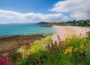 Scenic view of charming UK coastal towns with sandy beaches, colorful houses, and summer seaside atmosphere along the coastline.
